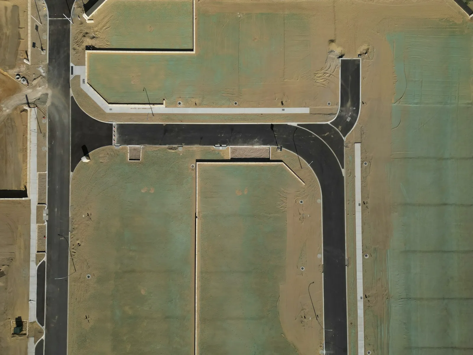 Aerial view of newly surfaced estate roads and kerb lines set out across a housing development site before the homes are built